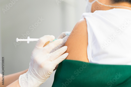 Nurse or doctor giving shot to senior female patient. Retired woman in medical face mask getting flu or Covid-19 vaccine injection in her arm.