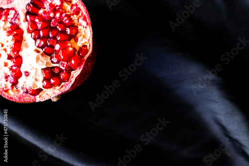 Bilde på lerret Close up photo of cut ripe red pomegranate on dark black fabric background