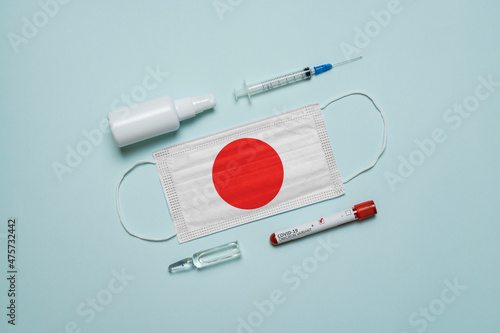 Blood tube for test detection of virus Covid-19 Omicron Variant with positive result, medicine mask with Japan flag superimposed and vaccine.  New Variant of the Covid-19 Omicron