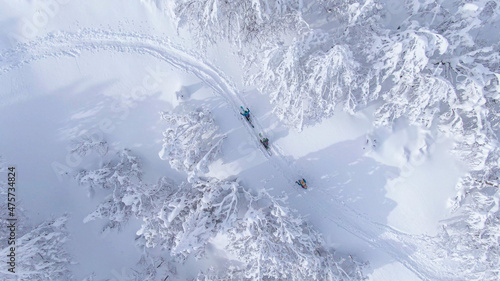 TOP DOWN: Flying above ski tourers hiking up a mountain covered in fresh snow photo