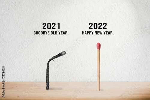 High quality photo. Post and banner Goodbye old year 2021. Happy new year 2022. Burnt and unused wood phosphorus. End and beginning of year concept. Gray empty wall and beige wooden floor background. 