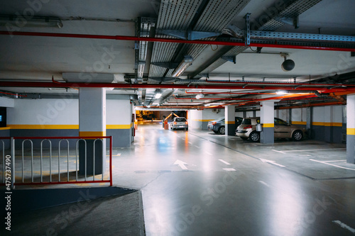 Cars in a large heated underground parking lot with lighting