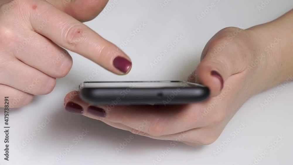 Female hands with red nails leaf through the tape or pages on the green screen of the phone. View from above. Approach movement. Female hands with red nails leaf through the tape or pages on the green screen of the phone. View from above. Approach movement.