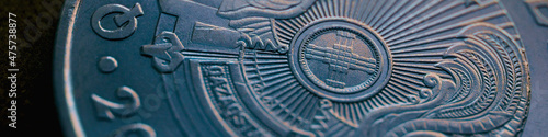 Fragment of Kazakh 50 tenge coin with the country emblem and focus on shanyrak. Close-up. Blue tinted banner or headline for Kazakh economy or state. Macro