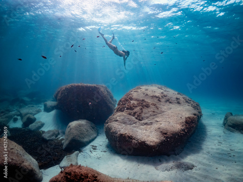 Fotografia Underwater view of girl with mask and fins diving very deep on a clear turquoise sea, rays of light trough the water