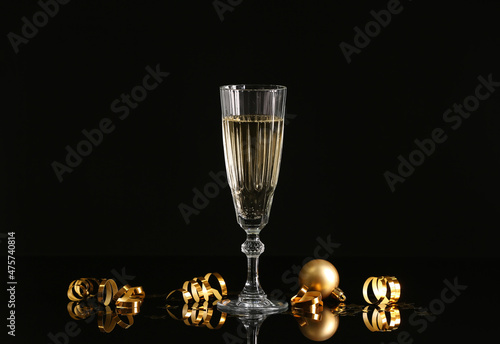 Glass of champagne and serpentine on dark background photo