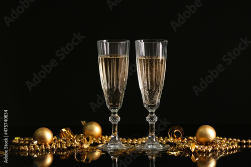 Glasses with champagne and Christmas decorations on black background photo