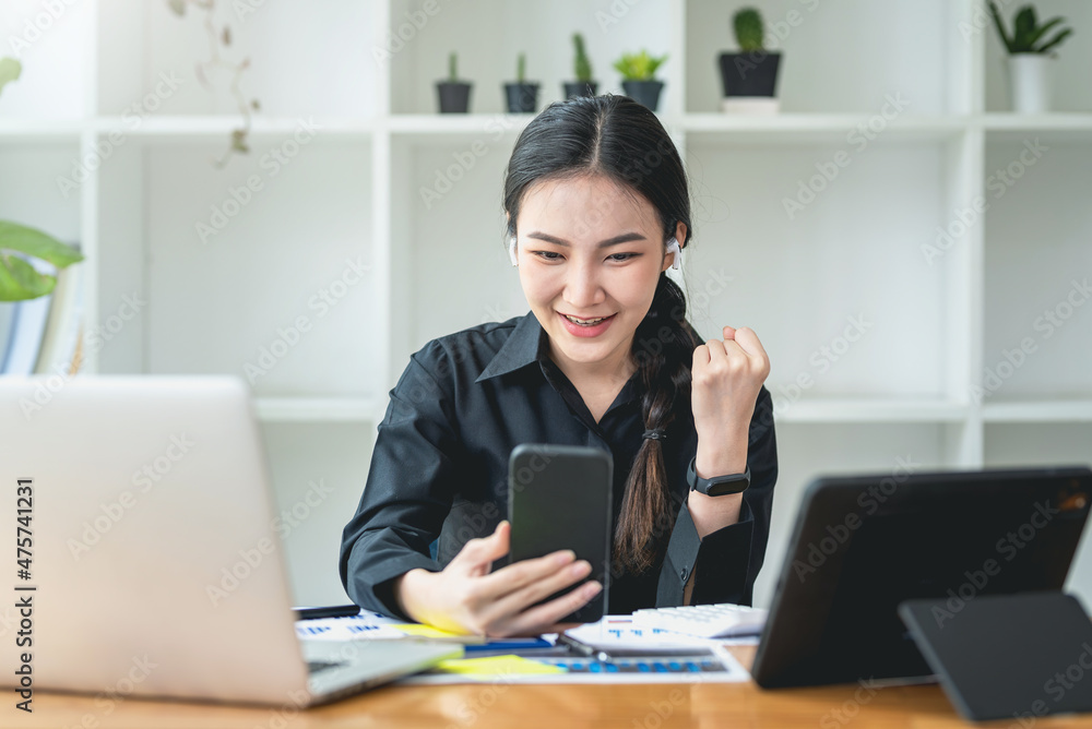 Emotional young Asian businesswoman expressing surprise checking reading messages with congratulation of winning on mobile phone at office. Emotional young Asian businesswoman expressing surprise checking reading messages with congratulation of winning on mobile phone at office.