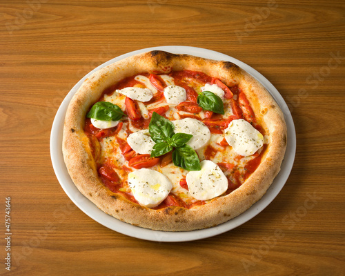 plate with pizza, cherry tomatoes, mozzarella and basil on wooden table