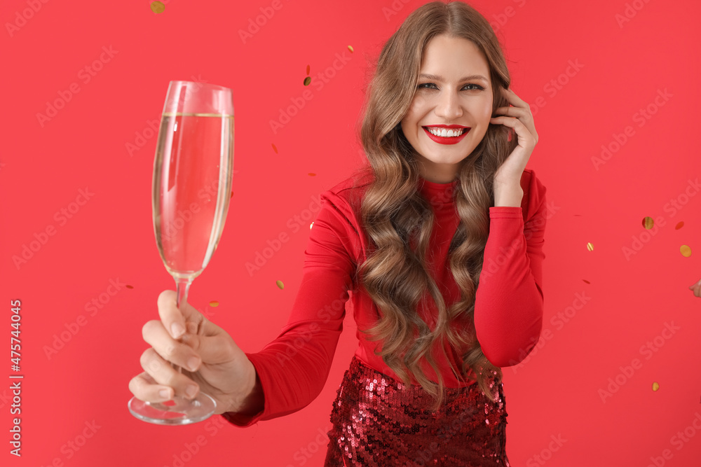 Beautiful young woman with champagne and falling confetti on color background Beautiful young woman with champagne and falling confetti on color background