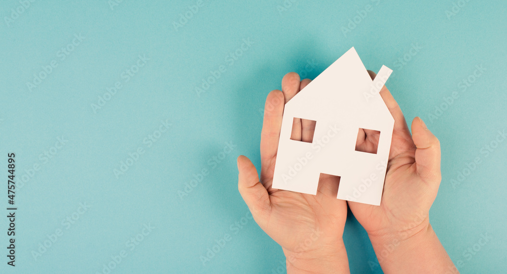 Holding a small paper house in the hands, planing to buy or rent a new home, real estate, owning property Holding a small paper house in the hands, planing to buy or rent a new home, real estate, owning property