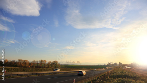 Samochody na drodze szybkiego ruchu, krajobraz wiejski przed zachodem słońca. 