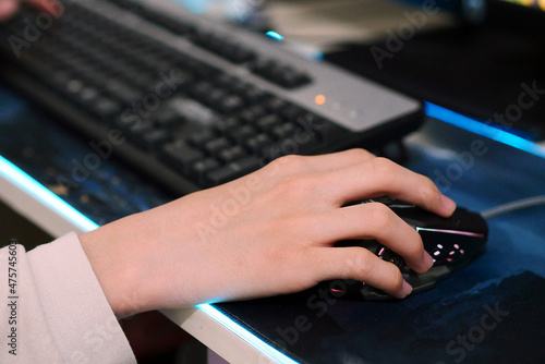 a person using a computer mouse, a person playing a game on a desktop computer using a mouse,