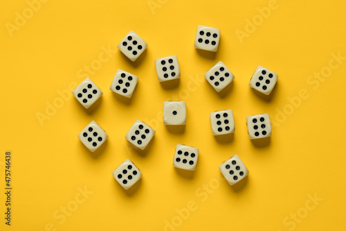 Dice on a yellow background, many sixes surrounded one unit. Top view. 