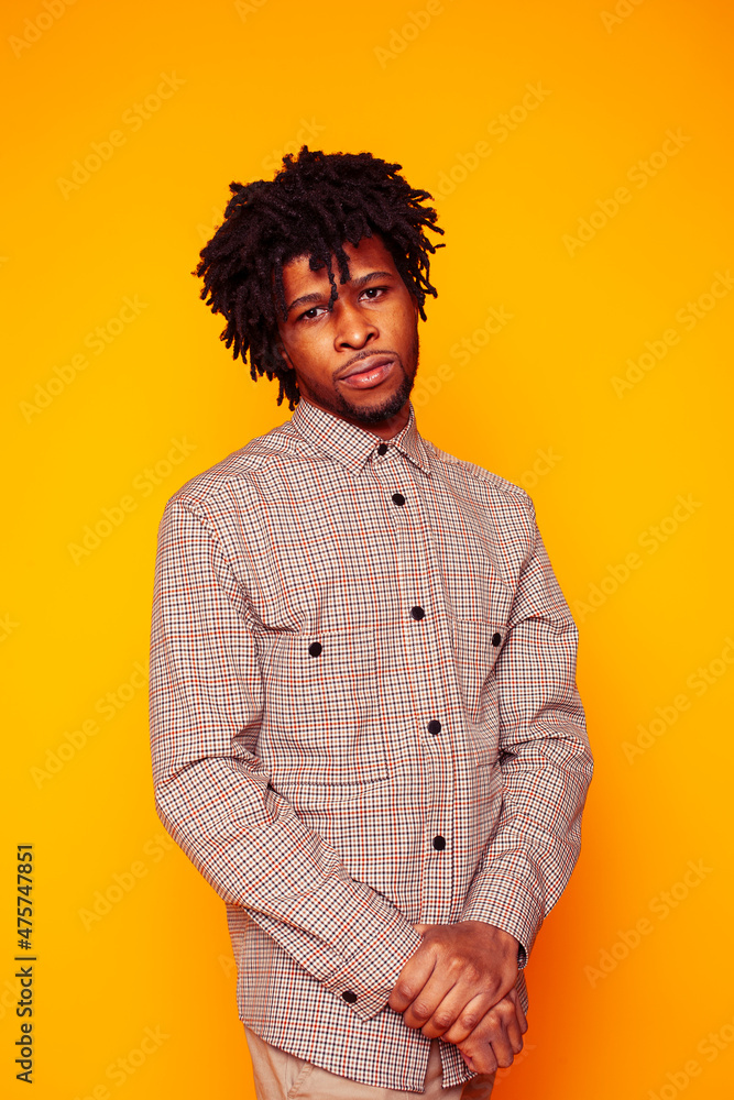 Fototapeta premium young handsome african american guy student posing cheerful and gesturing on yellow background, lifestyle people concept