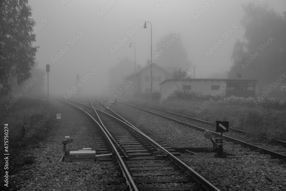 rural railway station and railroad tracks in the morning fog