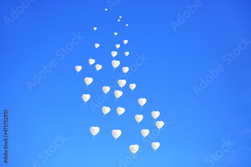 Białe balony w kształcie serc, dużego serca, szybujące na tle niebieskiego nieba, wesele, uczucia i emocie, zasoby graficzne.
