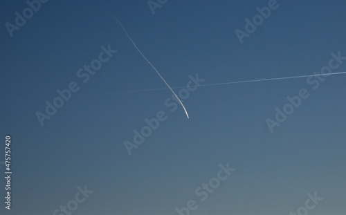 Kondensstreifen kreuzen sich vor blauem Himmel photo