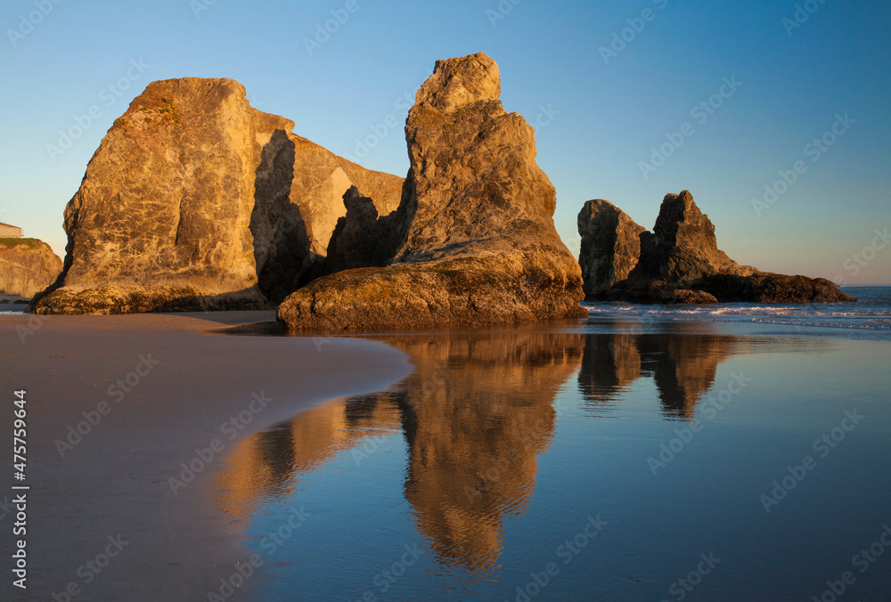Golden light on beautiful, natural sea stacks with stunning, smooth reflections on the beach in Bandon, Oregon
