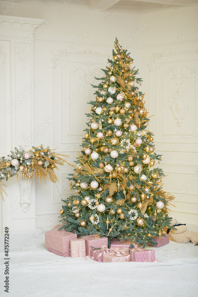 Large Christmas tree in gold and pastel pink colors in classic wite room Large Christmas tree in gold and pastel pink colors in classic wite room