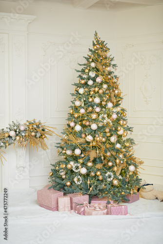 Large Christmas tree in gold and pastel pink colors in classic wite room