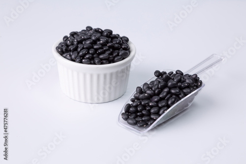 black bean in white bowl and plastic spoon on white background studio shot