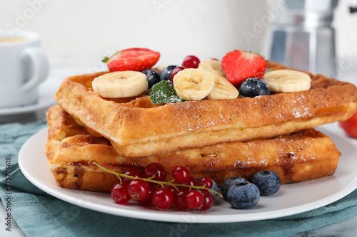 Delicious Belgian waffles with berries and banana on plate, closeup