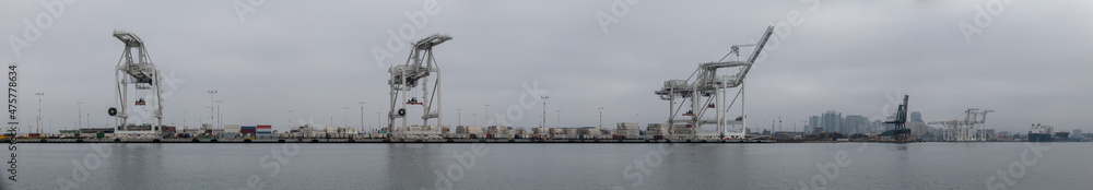 Inactive because of supply chain issues, cranes are quiet on a foggy day at the port of Oakland with Oakland skyline in background Inactive because of supply chain issues, cranes are quiet on a foggy day at the port of Oakland with Oakland skyline in background