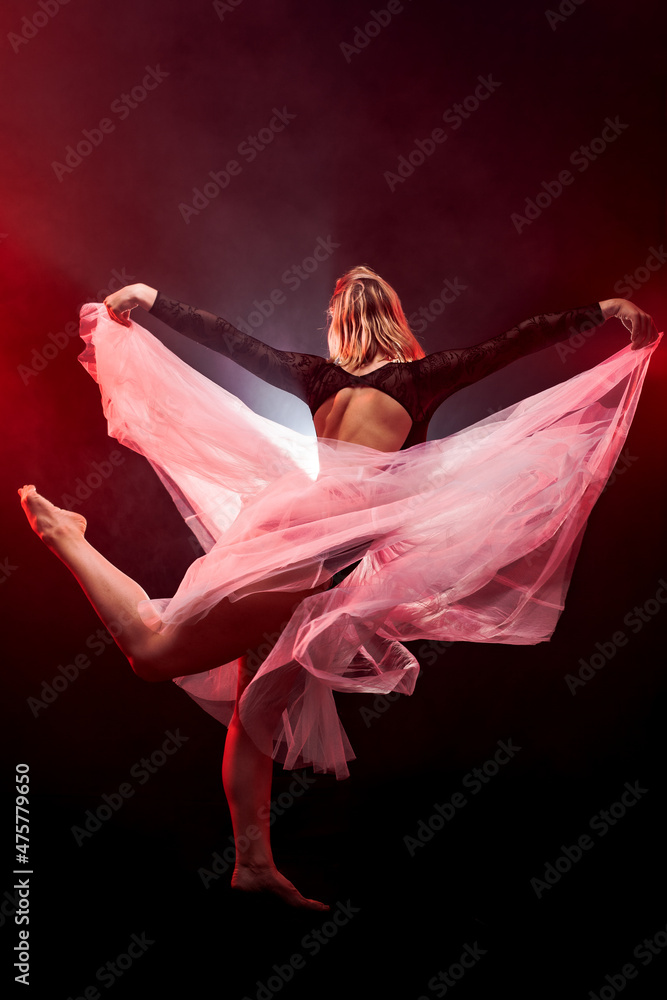 Fototapeta premium ballerina with a white dress and black top posing on red smoke background