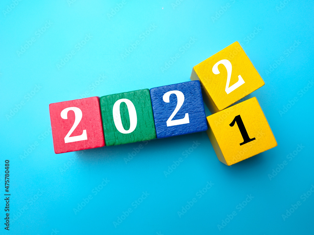 Colored wooden cube with 2021 change 2022 on a blue background. Colored wooden cube with 2021 change 2022 on a blue background.