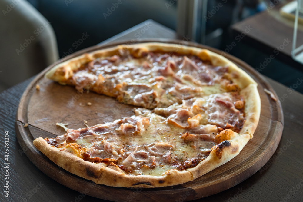 Close up on pizza on the wooden board on the table one piece missing Close up on pizza on the wooden board on the table one piece missing