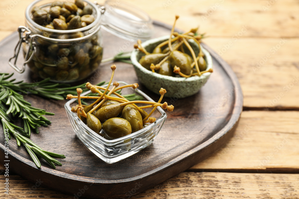 Delicious pickled capers and rosemary on wooden table