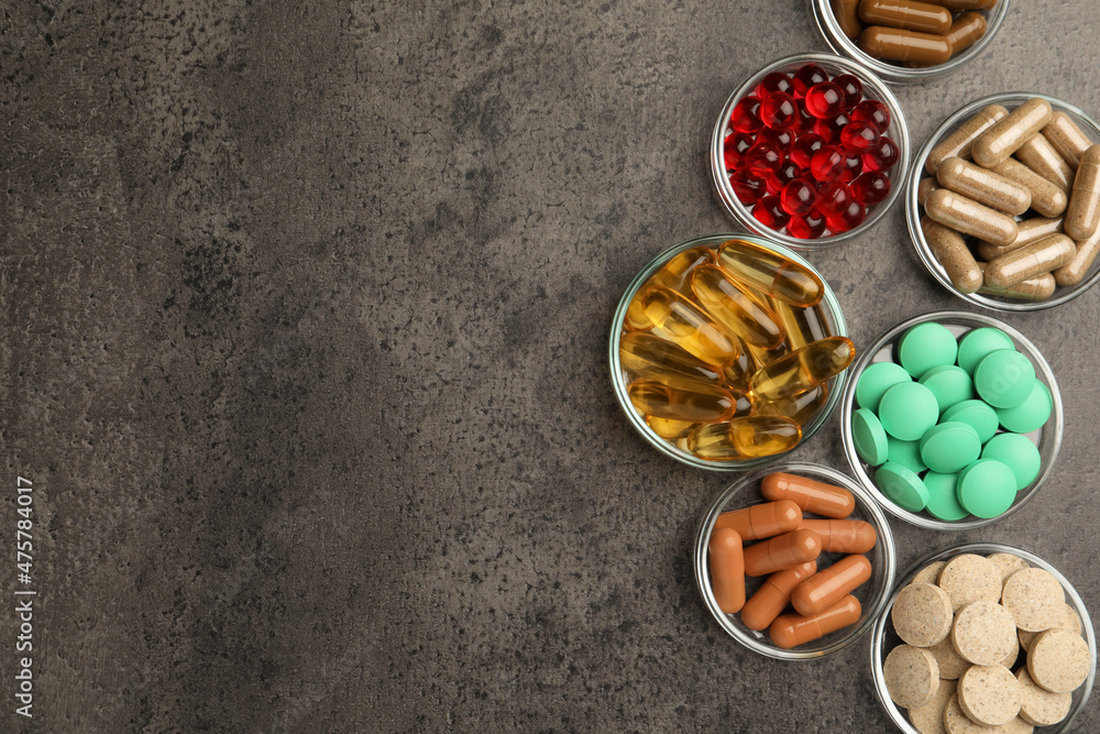 Different dietary supplements in glass bowls on grey table, flat lay. Space for text Different dietary supplements in glass bowls on grey table, flat lay. Space for text