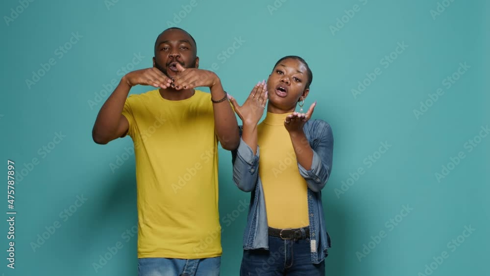 Man and woman blowing air kisses with hands and lips on studio camera. Romantic people flirting and sending kiss with palms, standing over isolated background. Seductive couple flirt Man and woman blowing air kisses with hands and lips on studio camera. Romantic people flirting and sending kiss with palms, standing over isolated background. Seductive couple flirt