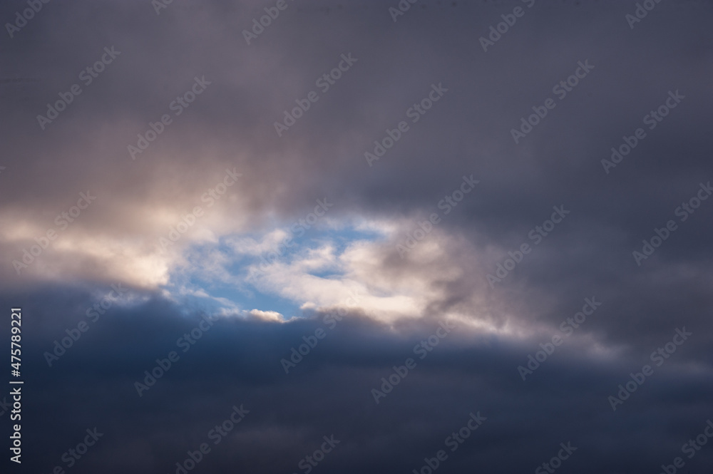 Naklejka premium The blue sky looks out among the dark winter clouds