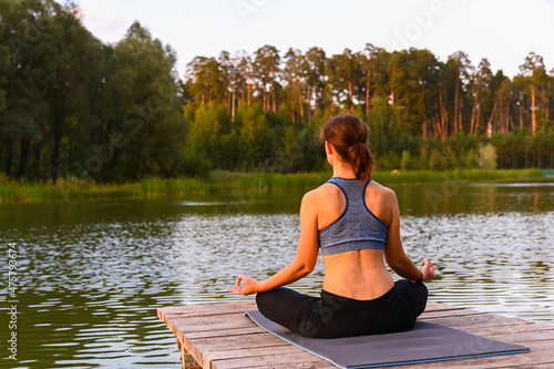 A woman meditates in nature by the lake. The concept of realizing the meaning of life.