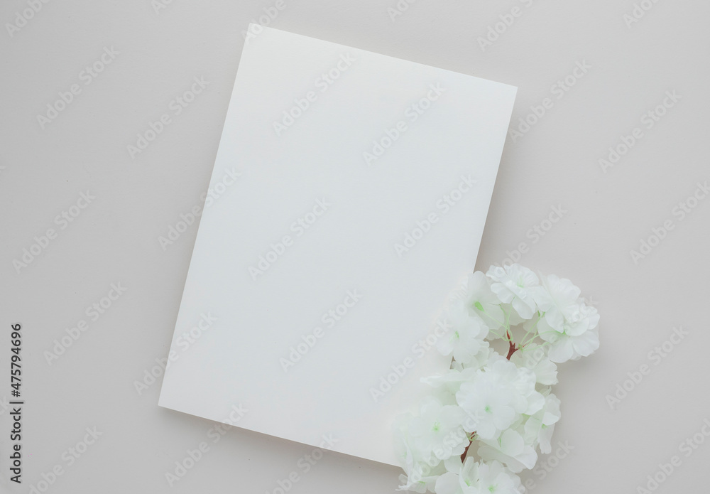White invitation card mockup with a white flower on beige background, Minimal beige workplace composition, flat lay, mockup White invitation card mockup with a white flower on beige background, Minimal beige workplace composition, flat lay, mockup