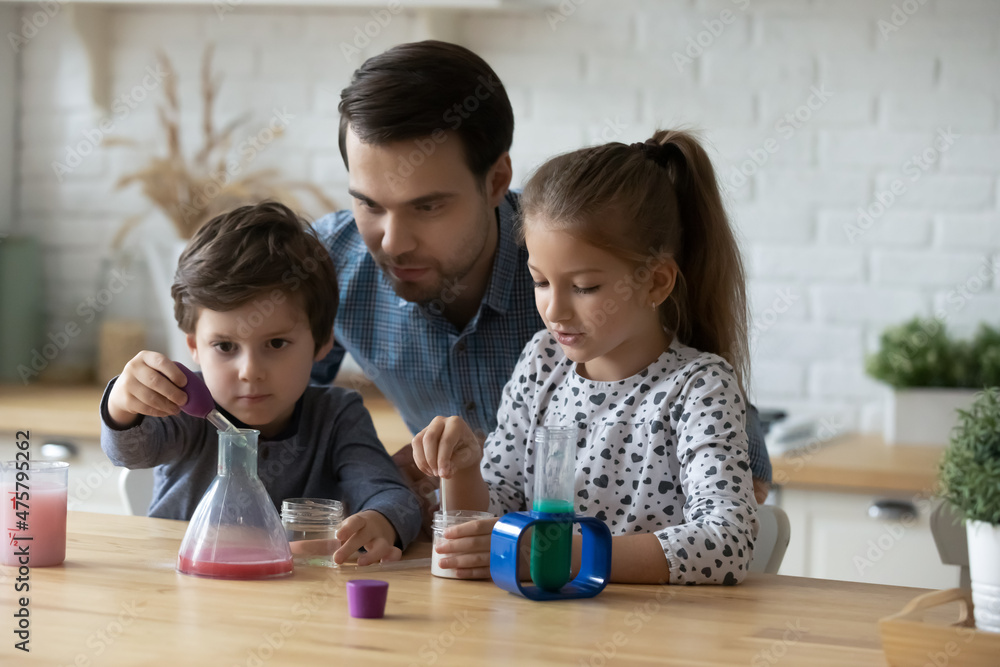 Caring father with little kids playing with toy laboratory, engaged in interesting educational activity, Caucasian young dad and children making experiments, spending leisure time at home together Caring father with little kids playing with toy laboratory, engaged in interesting educational activity, Caucasian young dad and children making experiments, spending leisure time at home together