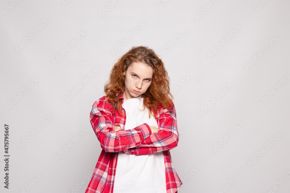 a young girl in a plaid shirt stands sad against a light background a young girl in a plaid shirt stands sad against a light background