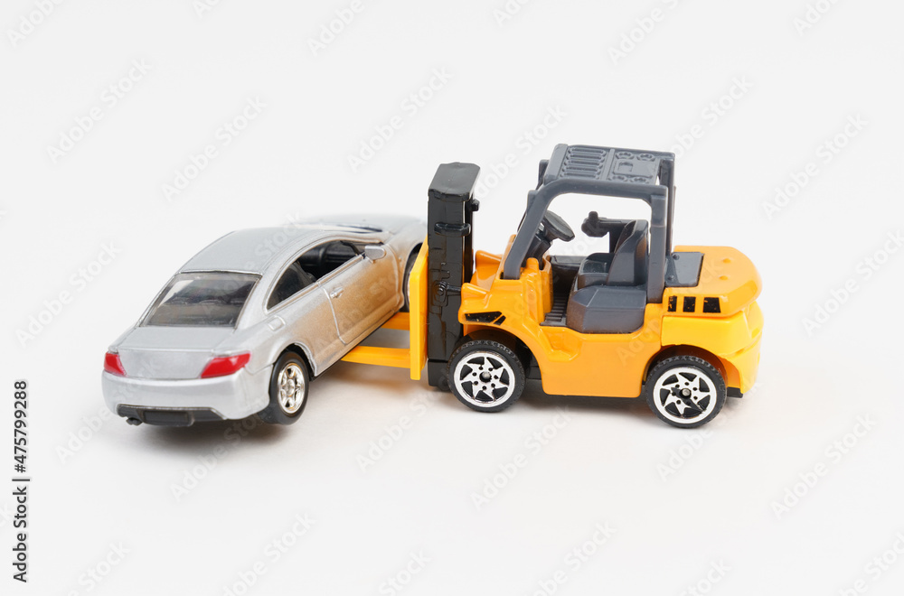 A loader moves a gray passenger car.