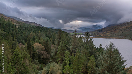 Epic aerial flying drone landscape image of Snowdon Massif viewed from above Llynau Mymber during Autumn sunset with dramatic sky