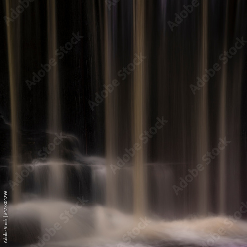 Epic beautiful Autumn landscape image of Nant Mill waterfall in Wales with glowing sunlight on the flowing water