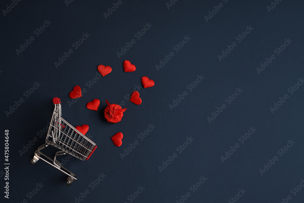 A grocery cart with a gift and hearts on a blue background. Picture for Valentine's Day. The concept of gifts and lovers. High-quality photography A grocery cart with a gift and hearts on a blue background. Picture for Valentine's Day. The concept of gifts and lovers. High-quality photography