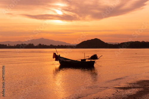 boat of fisherman on the beach with silhouette orange light before sunset and mountain background Asia Thailand