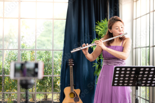 Flute classical instrument profestional player playing song.  A young and elegant Asian woman plays the flute. photo