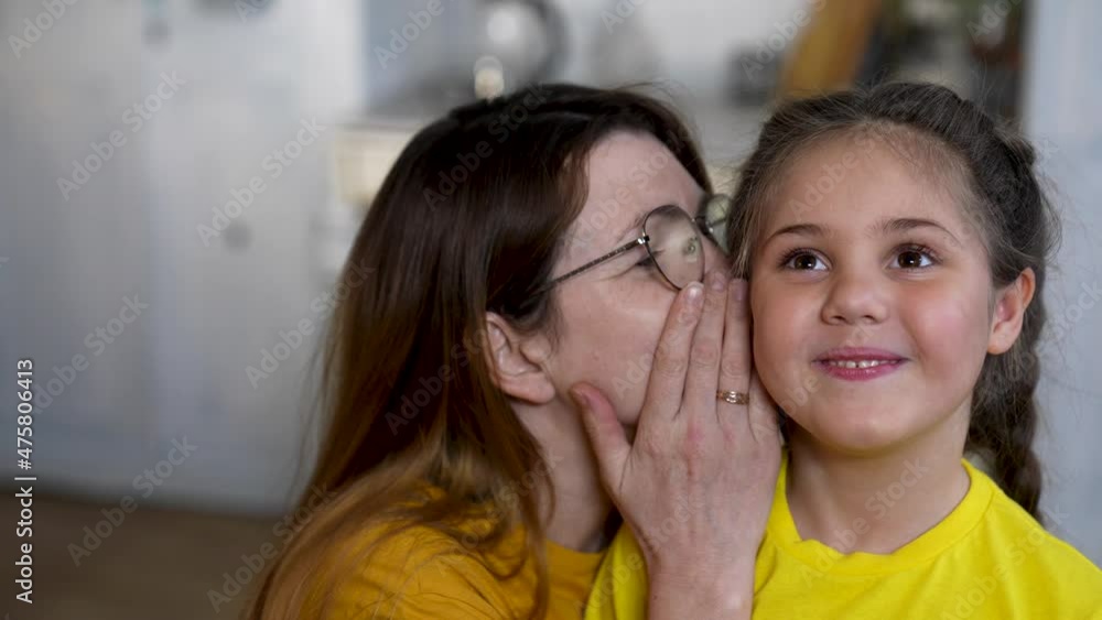 Mom and daughter are happy family. Girl whispers secret to her mother in her ear. Mom communicates with her daughter. Happy family concept. Mom whispers a secret in girl ear. Family games and fun.