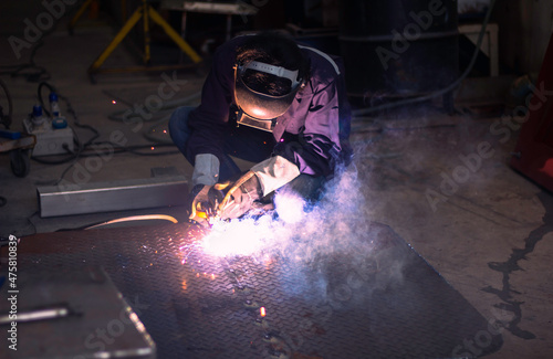 Skillful welders weld stainless steel in the factory. Construction site metal welder. builder wear fireproof gloves for safety at work. working on high