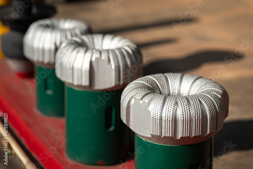 A polycrystalline carbide drill bit, using for drill a subsurface rock structure in oil drilling operation. Oil industrial heavy equipment object photo. Close-up and selective focus. photo