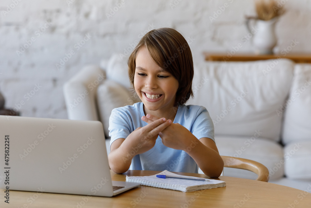 Happy teenage child boy looking at computer screen, making gestures, using sign language communicating online by video call with professional speech therapist, learning remotely alone at home. Happy teenage child boy looking at computer screen, making gestures, using sign language communicating online by video call with professional speech therapist, learning remotely alone at home.