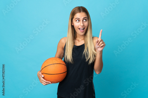 Young woman playing basketball  isolated on white background thinking an idea pointing the finger up © luismolinero